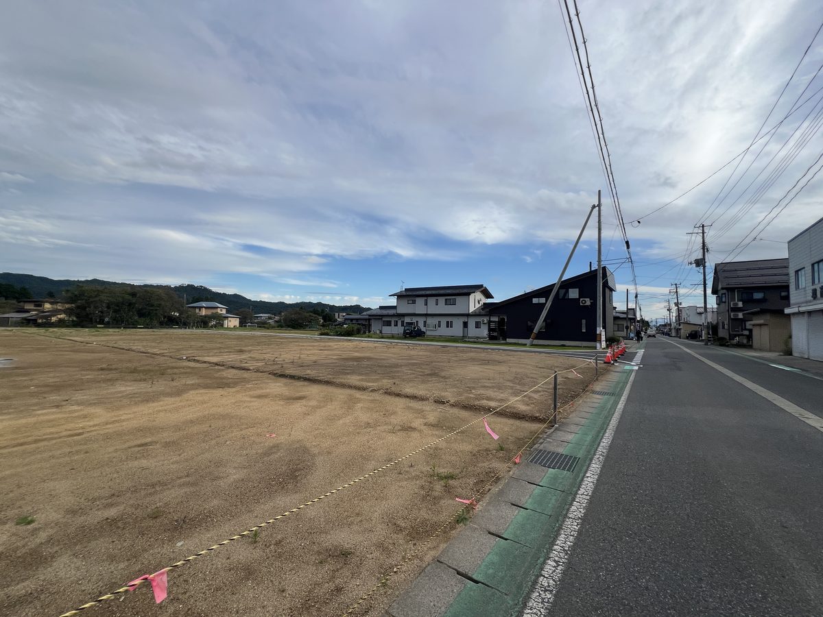 分譲地の脇を通る主要地方道 長井大江線と、まわりの住宅